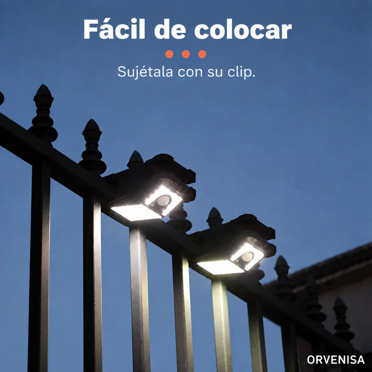 Foco solar sujeto con pinza a una valla de noche