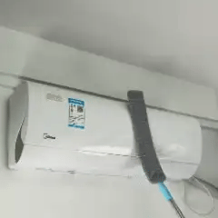 Orvenisa limpiando la parte superior de un aire acondicionado de pared